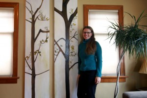 Summer stands next to her oil paintings on wood panels.