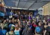 a band performs on an outdoor stage to a large crowd at the Come As You Are Music Festival