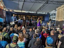 a band performs on an outdoor stage to a large crowd at the Come As You Are Music Festival