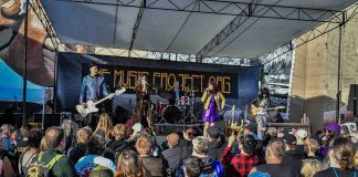 a band performs on an outdoor stage to a large crowd at the Come As You Are Music Festival