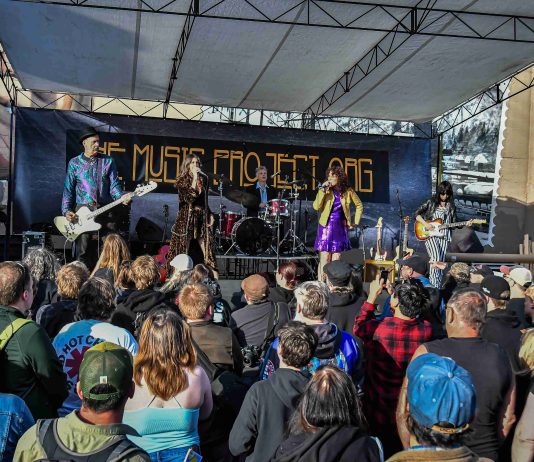 a band performs on an outdoor stage to a large crowd at the Come As You Are Music Festival
