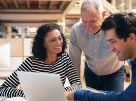 Smiling coworkers talking together over a laptop in an office