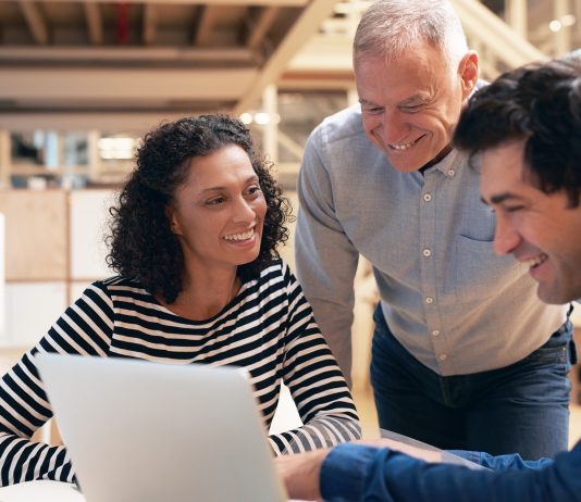 Smiling coworkers talking together over a laptop in an office
