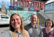 Marranda, Alex and Juliana pose for a selfie in front of a Venables truck and wall art with a blue design and the words Bellingham Farmers Market on it